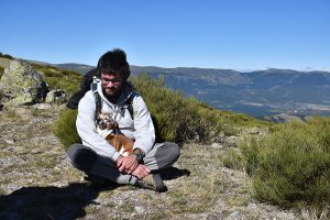 Hombre sentado en la naturaleza con su perro entre las piernas abrazados